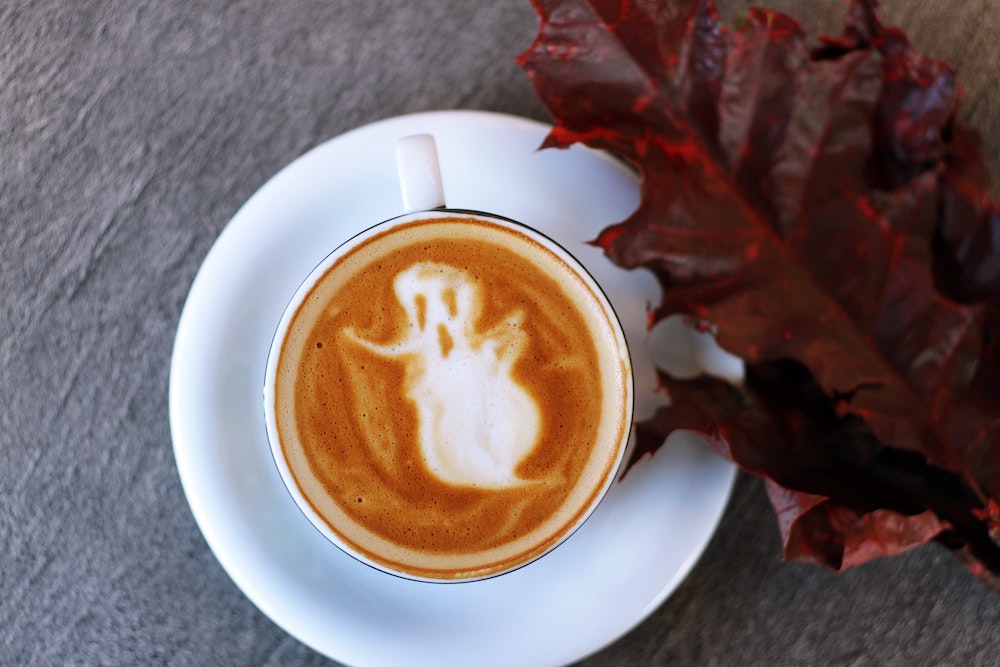 a coffee cup with a ghost as the espresso art